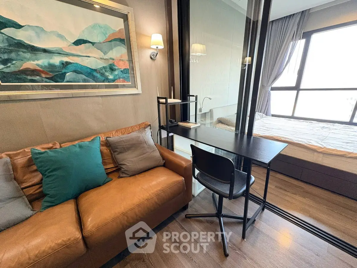 Modern studio apartment with cozy living area and glass partitioned bedroom, featuring stylish decor and natural light.