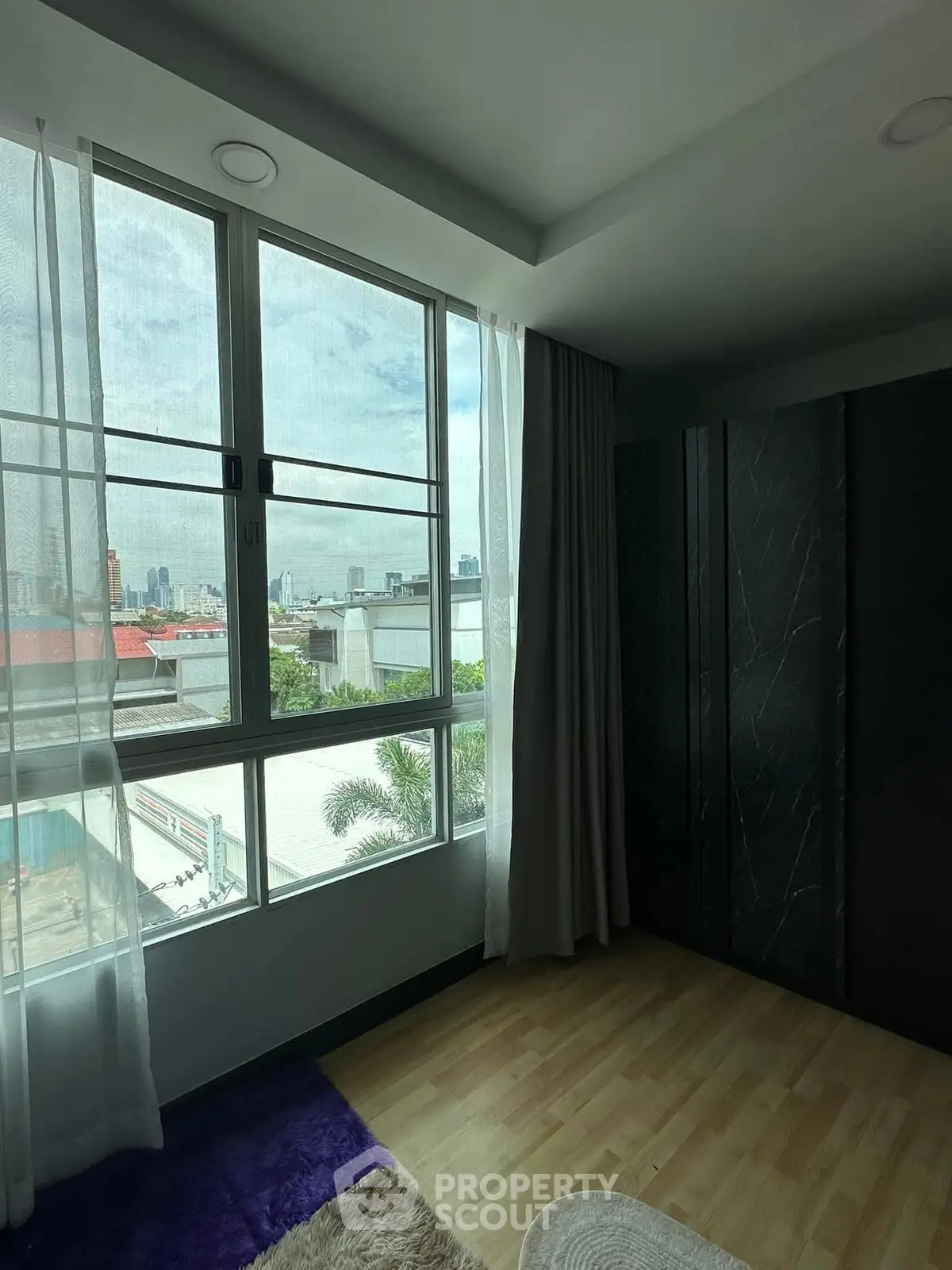 Spacious room with large windows offering a stunning city view, perfect for urban living.