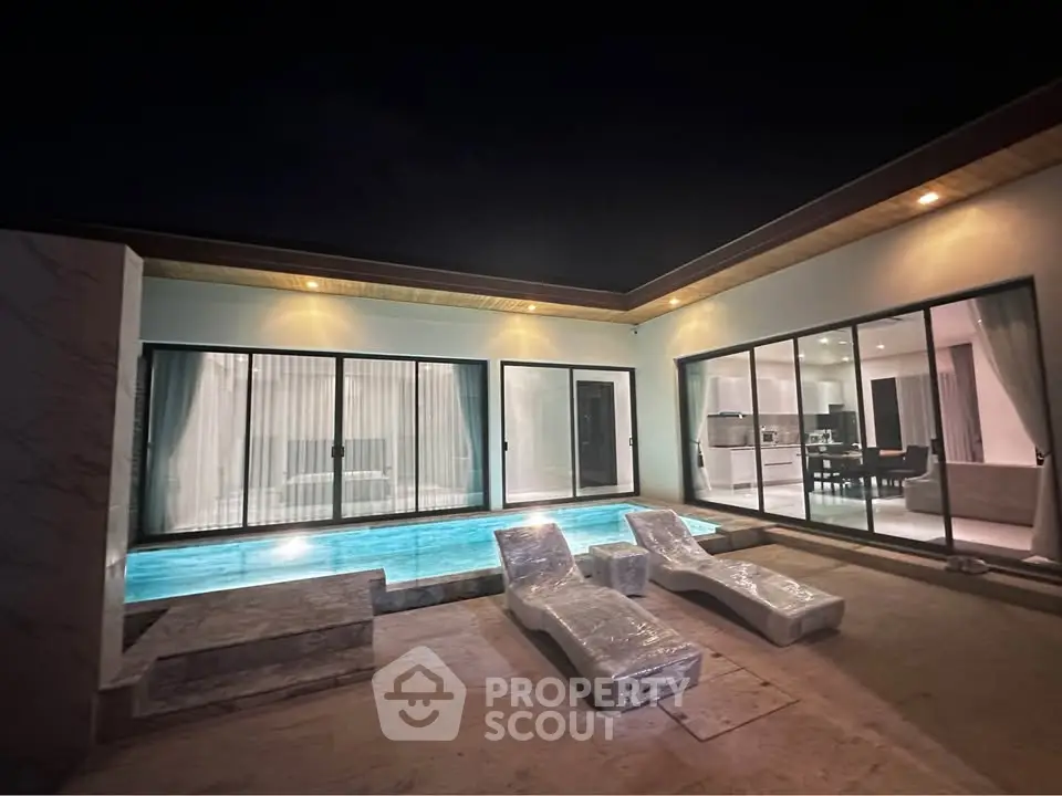 Luxurious modern villa with private pool and elegant outdoor lounge area at night.
