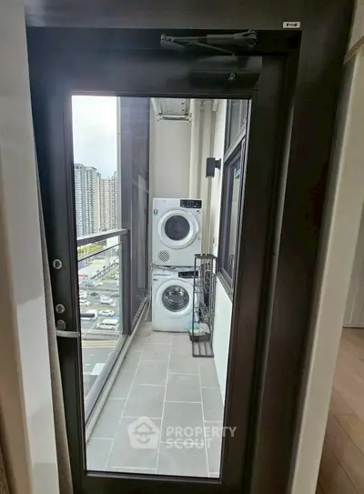Modern apartment balcony with washer and dryer, city view.