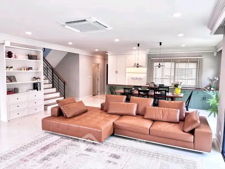 Spacious modern living room with stylish leather sofa and open kitchen layout
