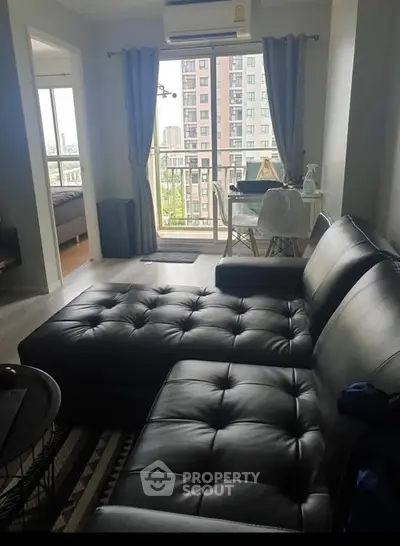 Modern living room with black leather sofa and balcony view in urban apartment