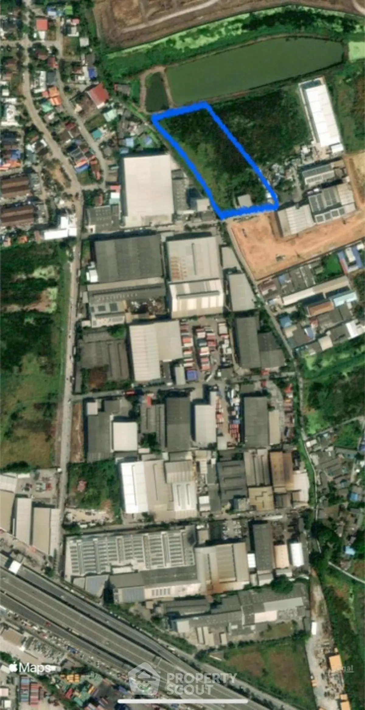 Aerial view of industrial area with marked land plot for development opportunities.