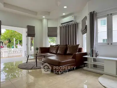 Spacious living room with modern leather sofa and large windows offering natural light.