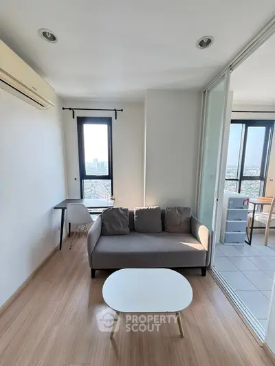Modern living room with city view, featuring sleek furniture and natural light.