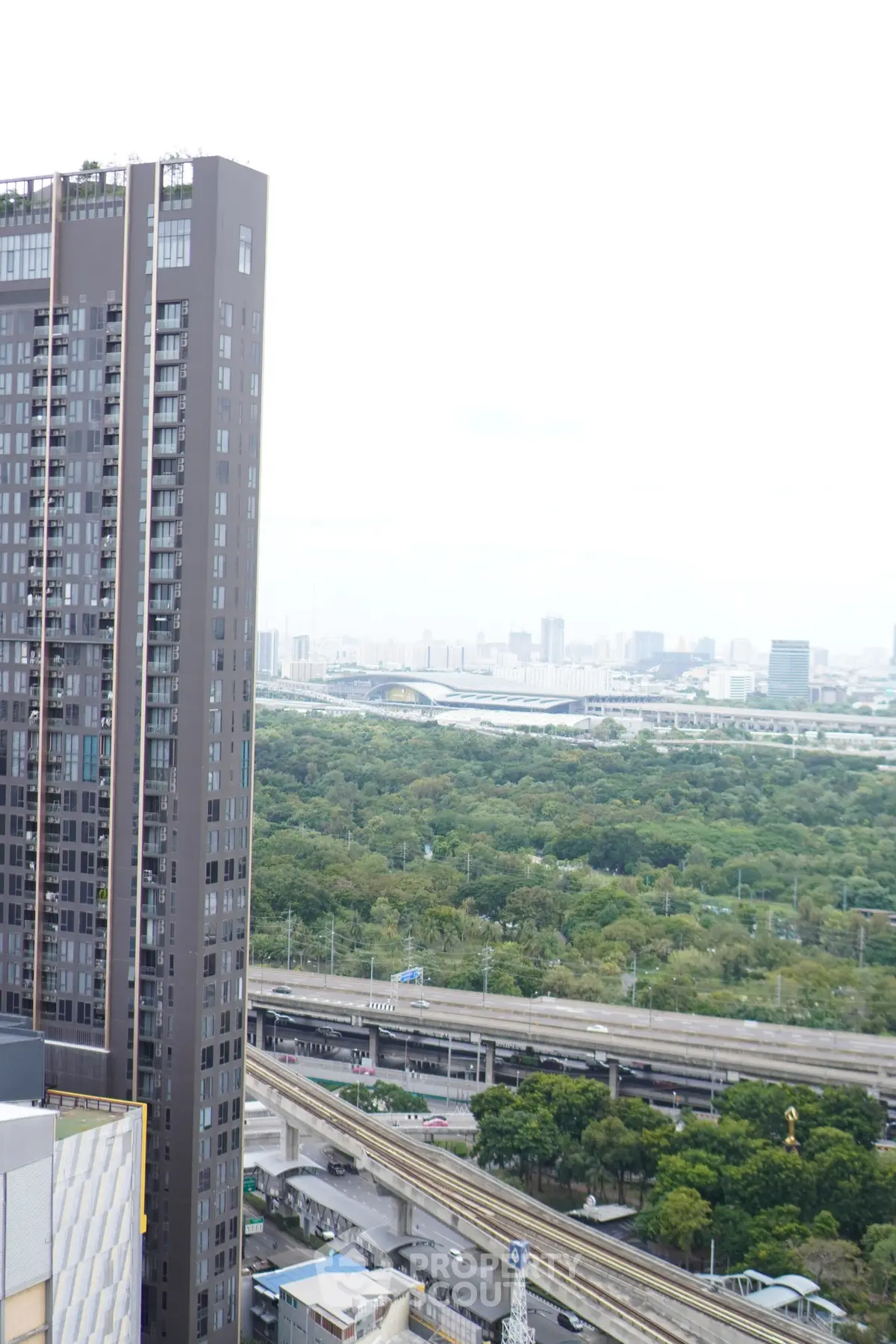 Stunning cityscape view from high-rise building with lush greenery and urban skyline.