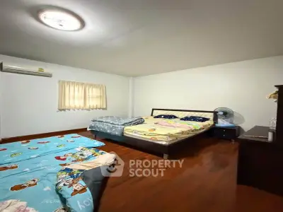 Spacious bedroom with wooden flooring and cozy bedding in a modern apartment.