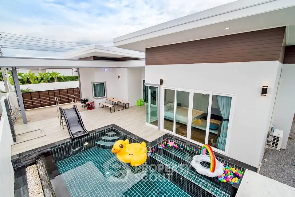 Modern home with private pool and playful inflatable toys, featuring sleek architecture and spacious outdoor area.