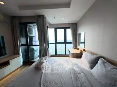 Spacious bedroom with large windows and scenic view, featuring modern decor and ample natural light.