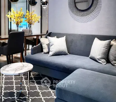 Elegant living room with modern gray sofa, stylish decor, and chic dining area.