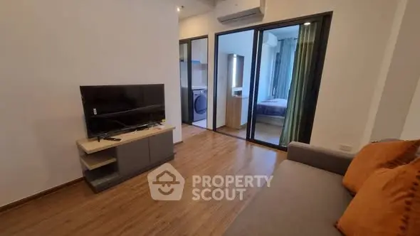 Modern living room with TV and view into bedroom and kitchen