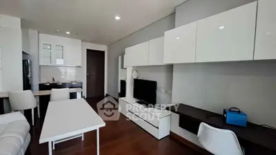 Modern living room with sleek white furniture and open kitchen layout in a stylish apartment.