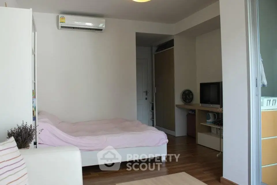 Cozy bedroom with wooden flooring, air conditioning, and modern furnishings in a stylish apartment.