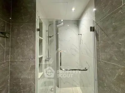 Luxurious modern bathroom with sleek glass shower and elegant marble tiles.