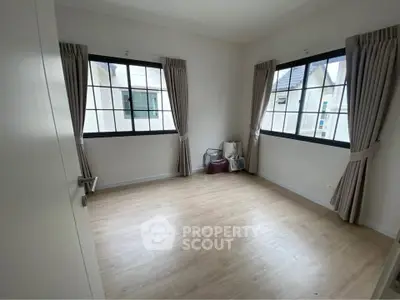 Spacious empty room with large windows and wooden flooring, perfect for customization.