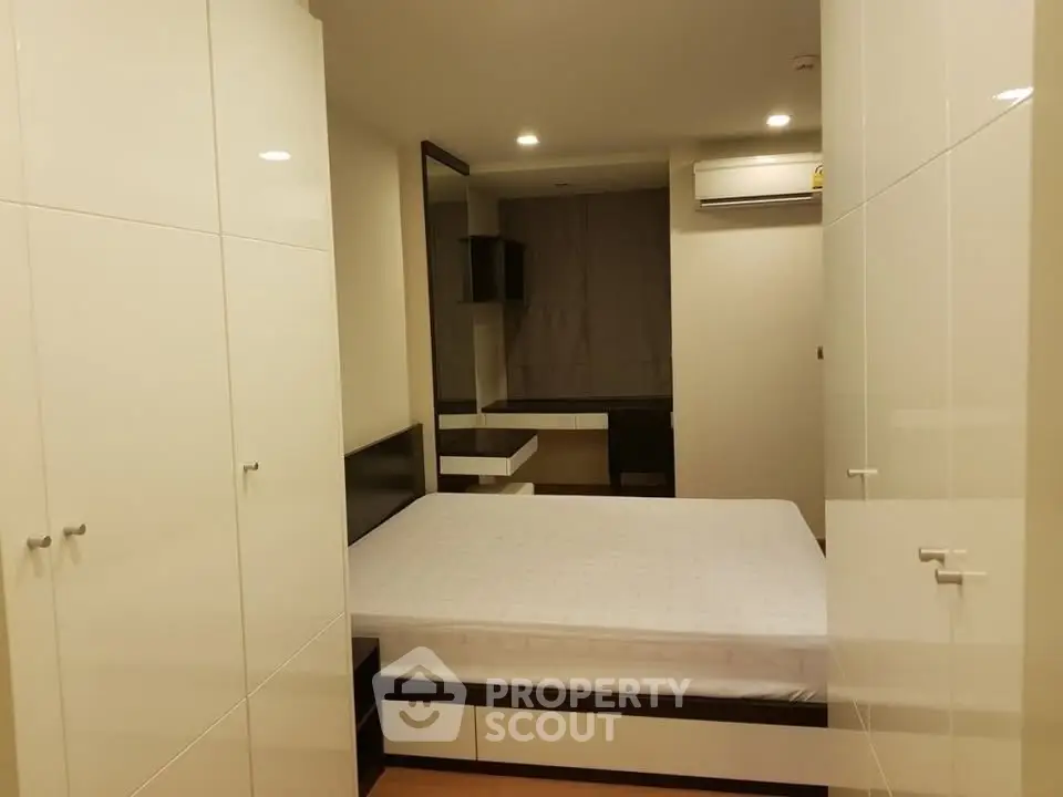 Modern bedroom with sleek white wardrobes and cozy ambiance.