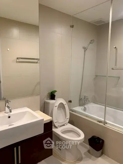 Modern bathroom with sleek fixtures and a glass-enclosed bathtub in a contemporary apartment.
