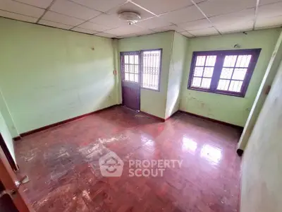 Spacious empty room with wooden flooring and natural light from windows.