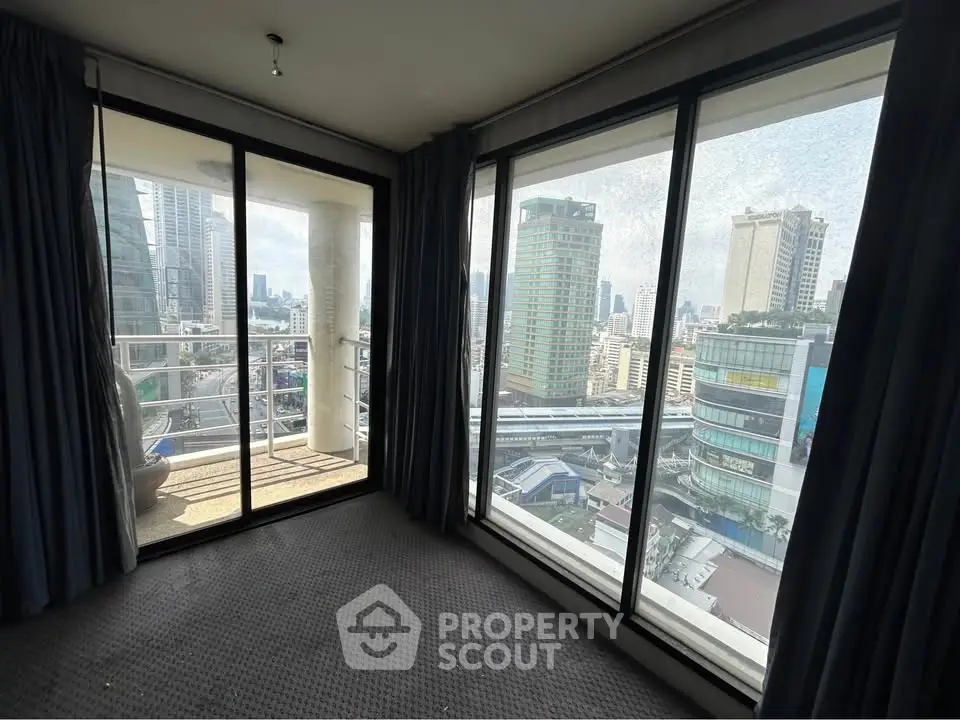 Stunning city view from high-rise apartment with floor-to-ceiling windows and balcony access.