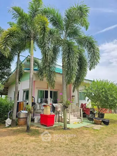 Charming single-story house with lush palm trees and vibrant garden, perfect for serene living.