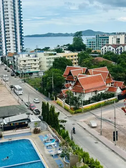 Stunning aerial view of urban landscape with pool, modern buildings, and scenic ocean backdrop.