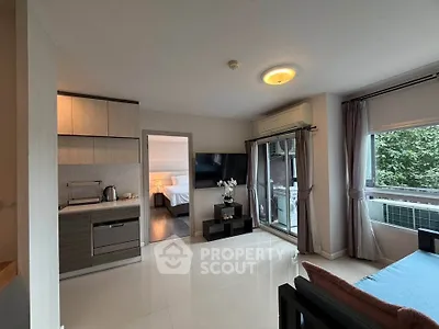 Modern open-plan living room with kitchen and bedroom view, featuring large windows and stylish decor.