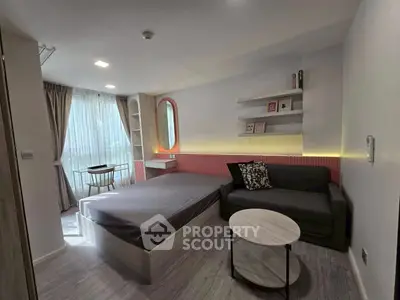 Modern bedroom with stylish decor, featuring a cozy bed, sleek sofa, and natural light from large window.