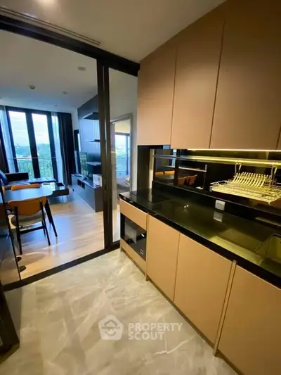 Modern open-layout kitchen with sleek cabinetry and adjacent living area with large windows.
