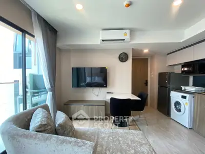 Modern living room with open kitchen, featuring sleek furniture and appliances, ideal for urban living.
