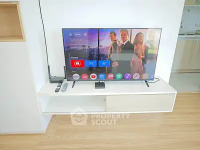 Modern living room with sleek TV setup and stylish wooden flooring.