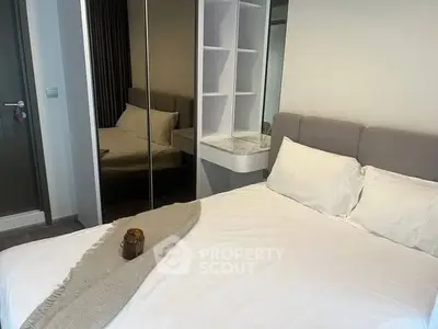 Modern bedroom with mirrored wardrobe and cozy bedding in stylish apartment.