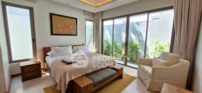 Luxurious bedroom with large windows and garden view, featuring elegant decor and cozy seating area.