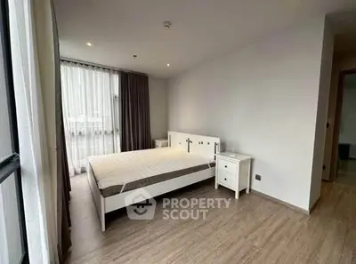 Spacious bedroom with large window and modern furnishings