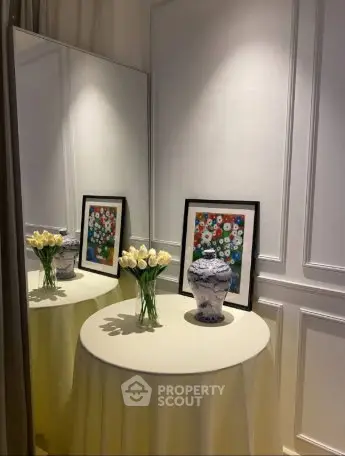 Elegant interior corner with decorative vase and framed art on round table.