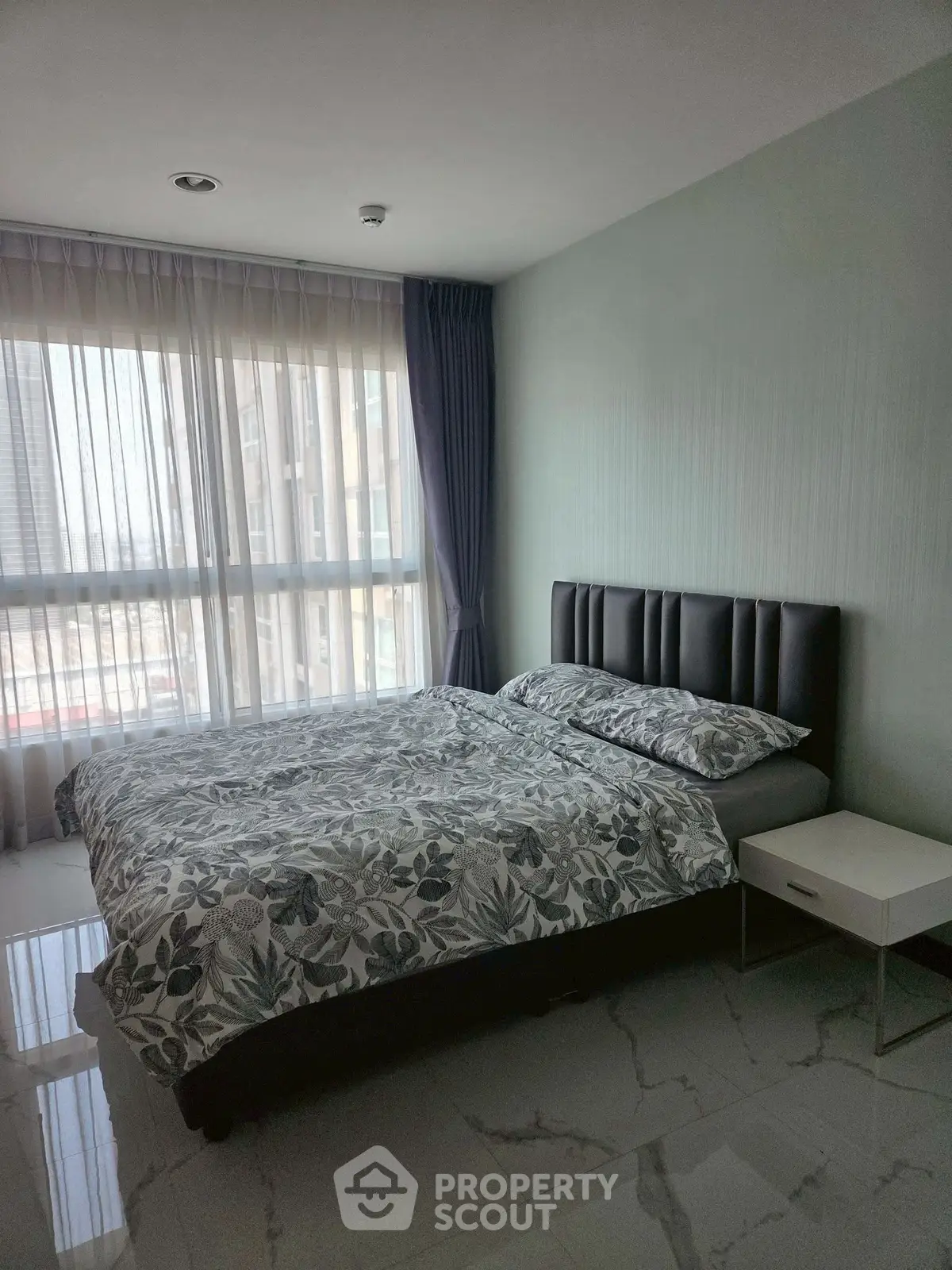 Modern bedroom with large window and stylish decor in a high-rise apartment.