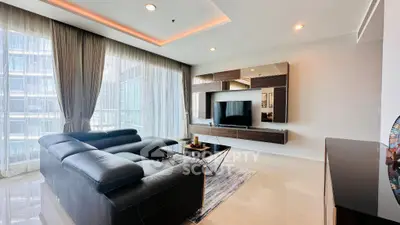 Luxurious modern living room with sleek leather sofa and large TV, featuring floor-to-ceiling windows.