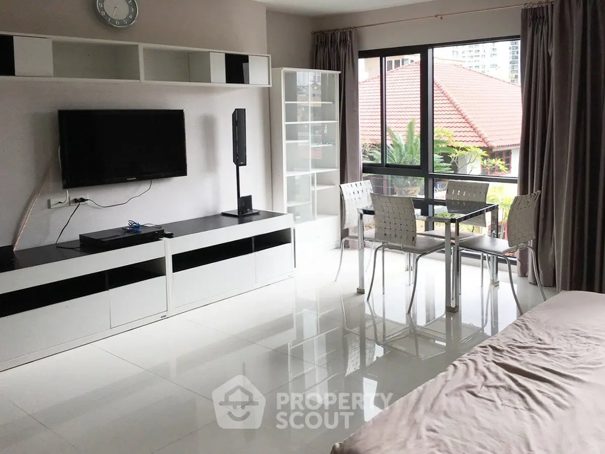 Modern living room with sleek furniture and large windows offering natural light and garden view.