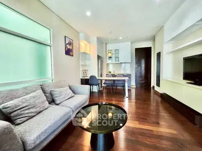 Modern living room with open kitchen, sleek furniture, and hardwood floors in a stylish apartment.