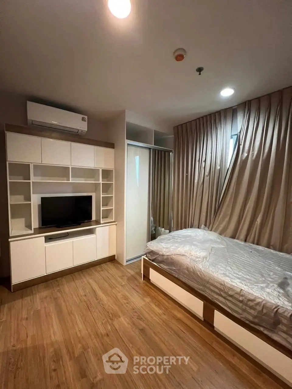 Modern bedroom with wooden flooring and built-in storage in a cozy apartment.