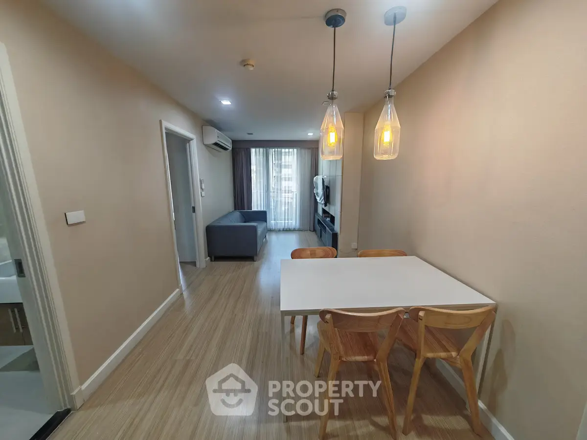 Modern living room with dining area, featuring stylish lighting and wooden flooring in a cozy apartment.