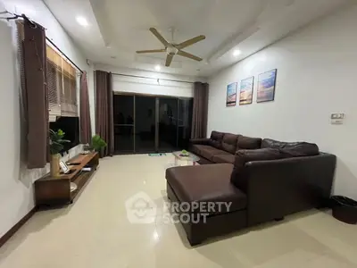 Spacious living room with modern brown sectional sofa and large windows.