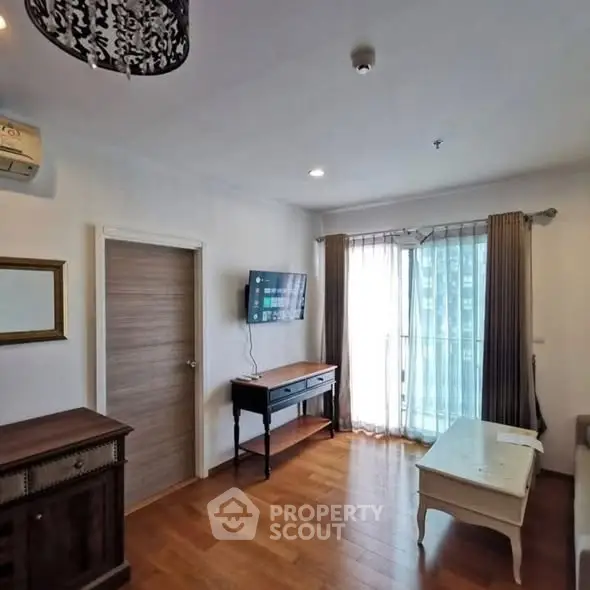 Charming living room with wooden flooring, modern furniture, and natural light from large window.