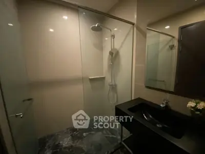 Modern bathroom with sleek shower and elegant black sink in a contemporary real estate property.