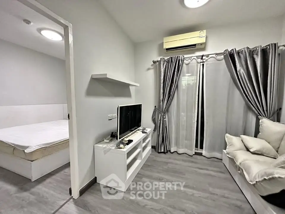 Modern living room with sleek design and adjacent bedroom, featuring stylish decor and natural light.