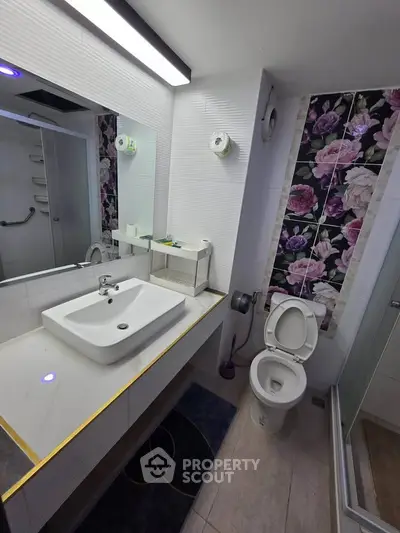 Modern bathroom with floral accent wall and sleek fixtures in a stylish apartment.