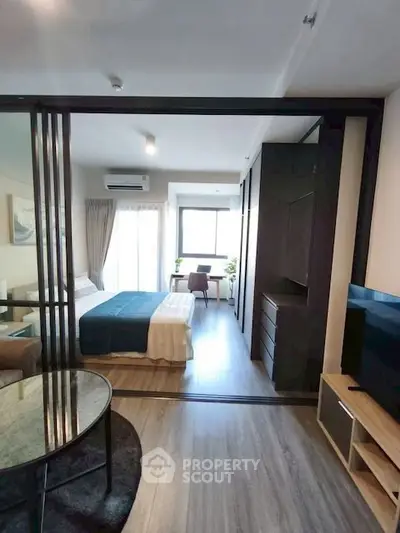 Modern studio apartment with sliding glass doors, cozy bed, and stylish decor.