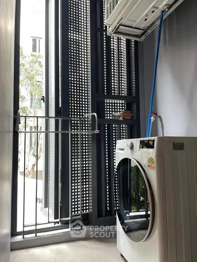 Modern laundry area with washing machine and drying rack in sleek apartment
