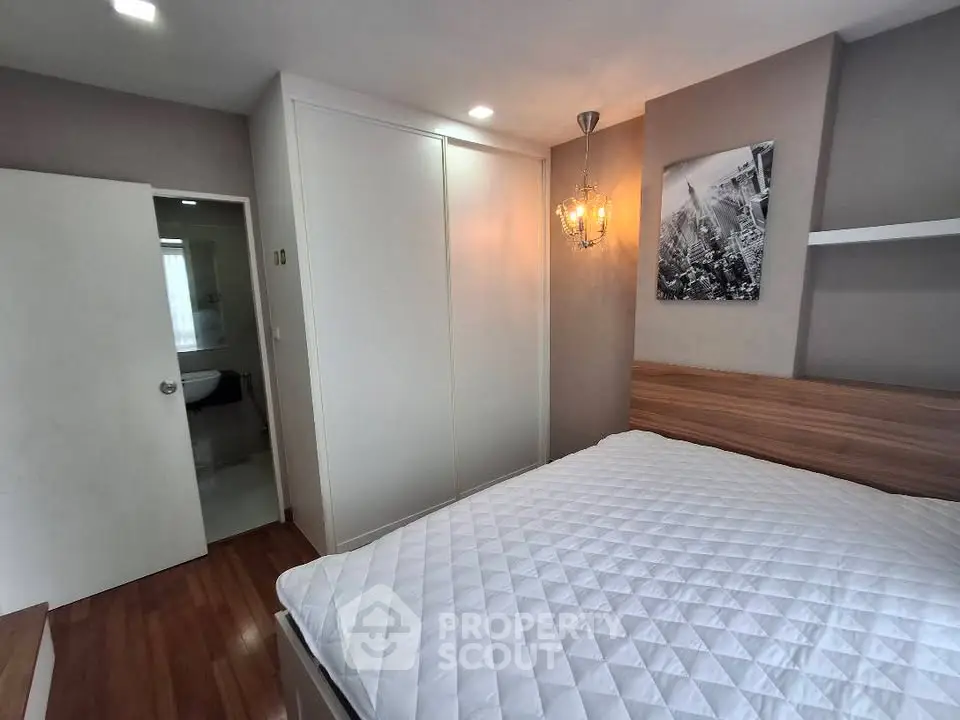 Modern bedroom with wooden flooring and elegant lighting