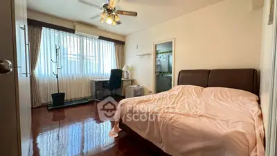 Cozy bedroom with ensuite bathroom and study area, featuring polished wooden floors and natural light.