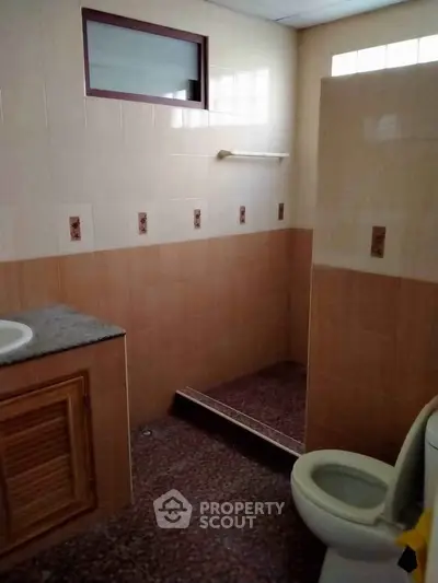 Simple bathroom with tiled walls and floor, featuring a toilet and sink.